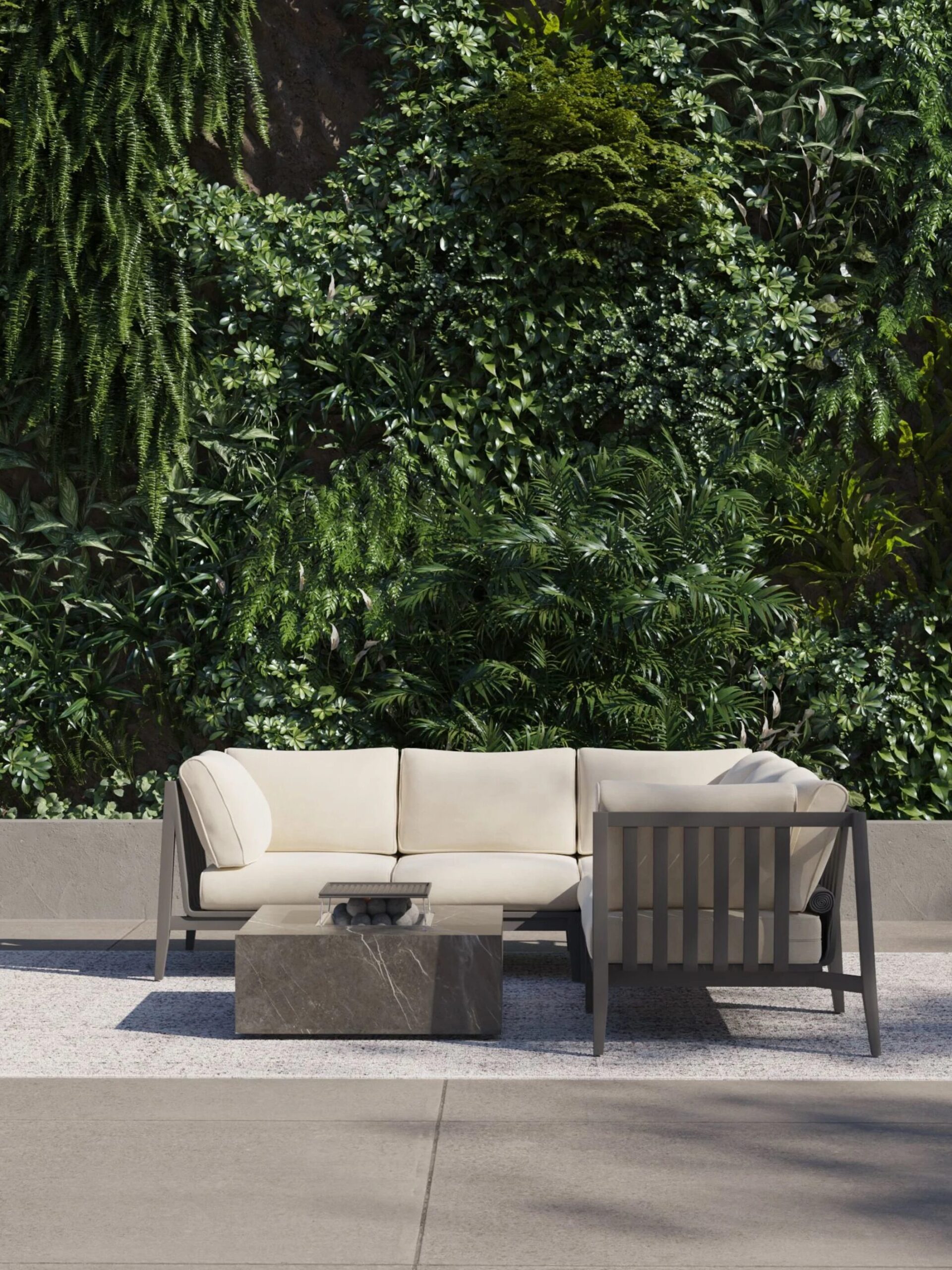 Outdoor seating area with a beige cushioned sofa and a dark square coffee table on a light rug, set against a lush vertical garden backdrop.