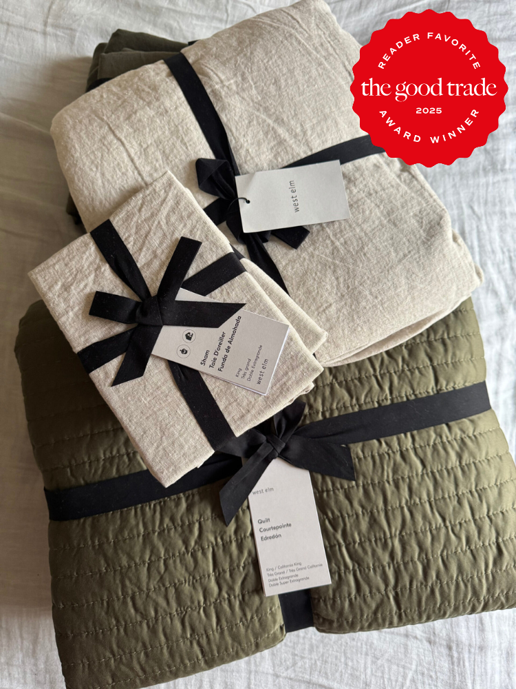 Folded green and beige bedding sets with black ribbons and tags, stacked on a white surface. A red "The Good Trade 2025 Award Winner" badge is in the top right corner.