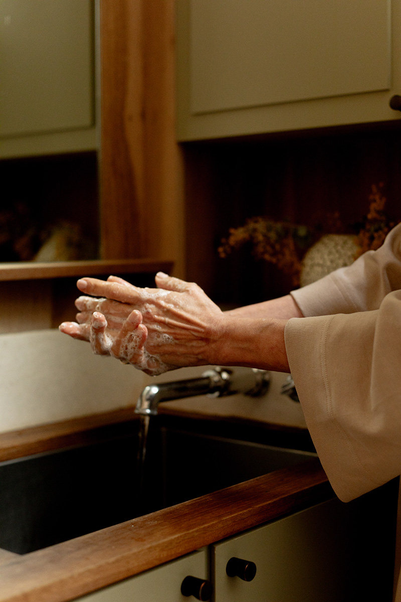 A person washing their hands with soap at a sink in a kitchen or bathroom.