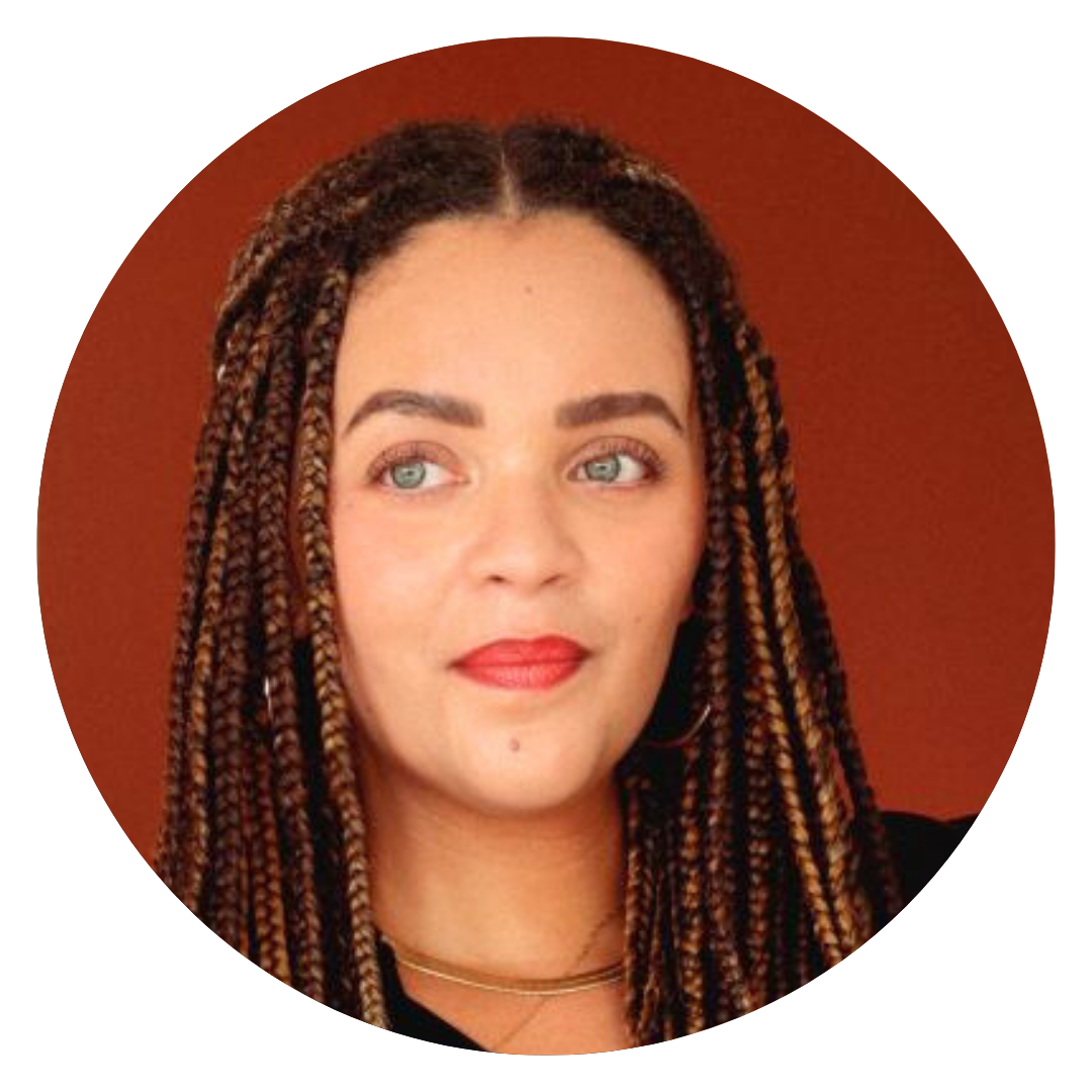 A woman with long, braided hair and light eyes is looking slightly to the side. She is wearing a black top and a gold necklace, with a solid reddish-brown background.