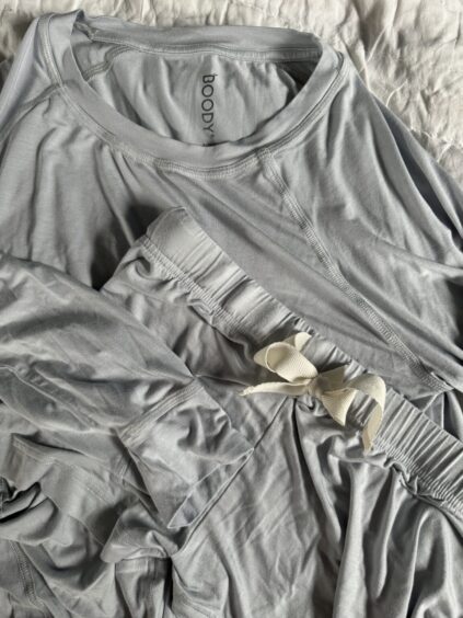 Light gray long-sleeve shirt and elastic-waist pants with a drawstring, both made of soft fabric, laid out on a white surface.