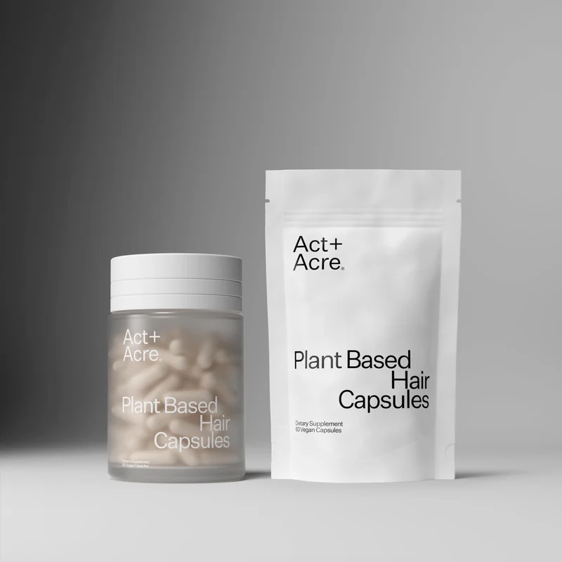 A jar and a resealable pouch, both labeled "Act+Acre Plant Based Hair Capsules," are displayed against a plain gray background.