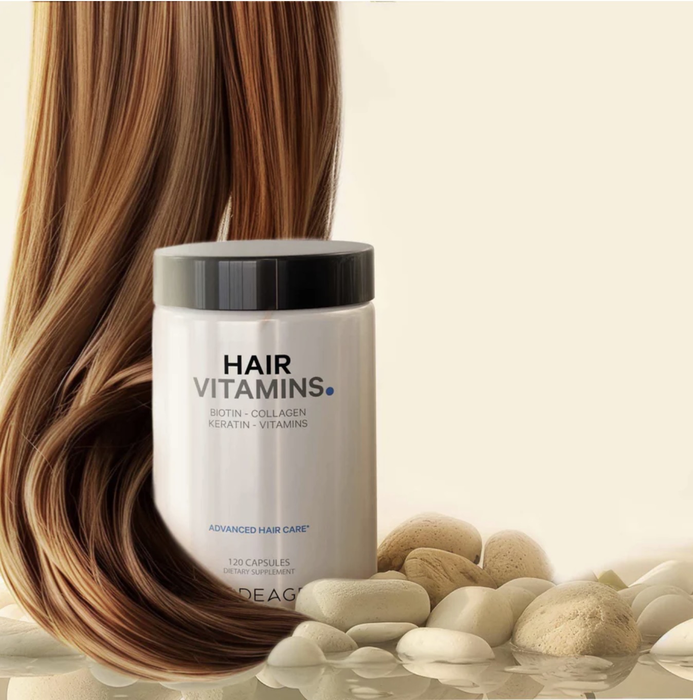 A container labeled "Hair Vitamins" is placed on smooth stones with a lock of long, brown hair draped around it and a light beige background.