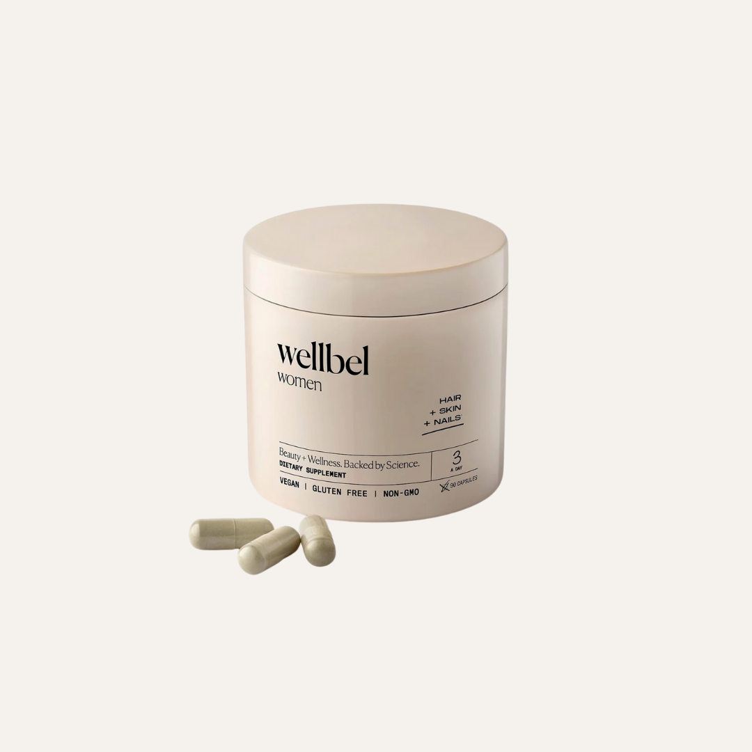 A container of Wellbel Women dietary supplement with three white capsules placed beside it on a plain background.