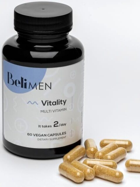 A bottle labeled "Beli MEN Vitality Multi Vitamin" with 60 vegan capsules is shown next to several loose yellow capsules on a white background.