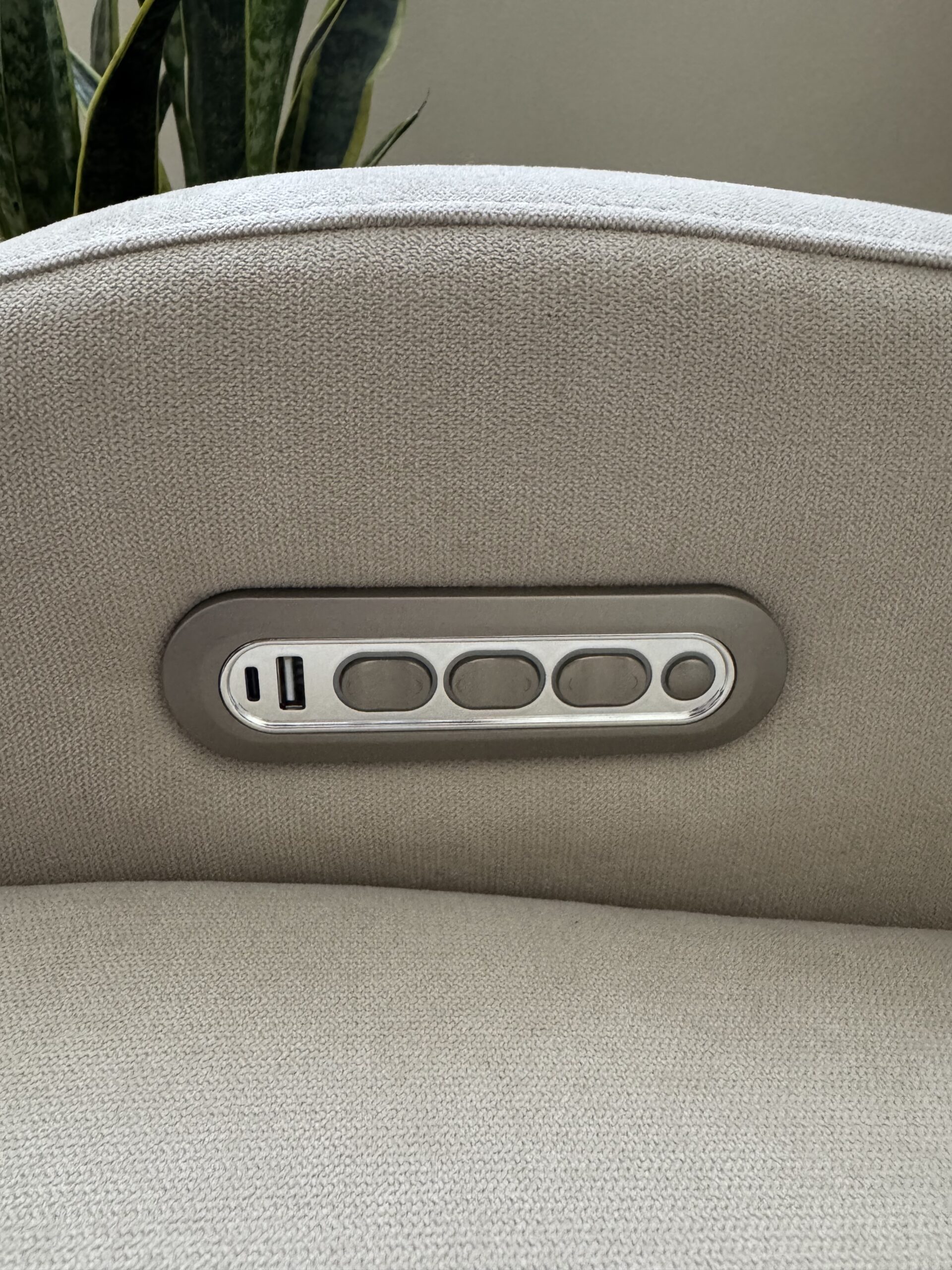 Close-up of a chair armrest showing built-in control buttons and a USB port set in a metallic panel.