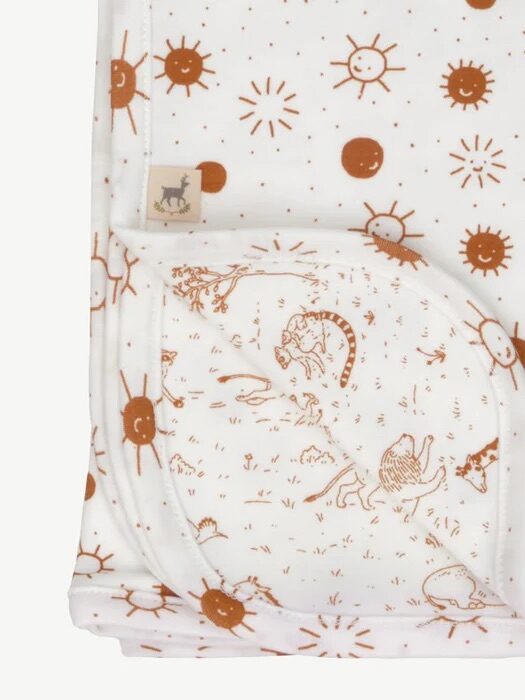 A white baby blanket with brown illustrations of suns, dinosaurs, and prehistoric scenes, partially folded to show the pattern on both sides.
