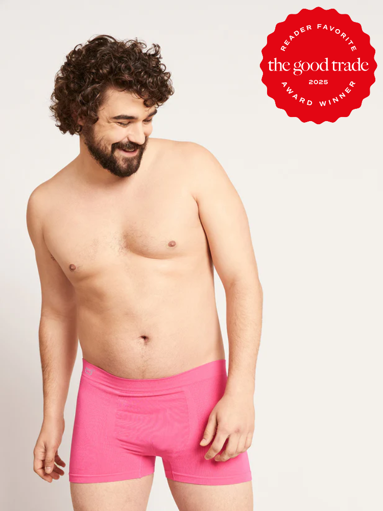 A man wearing bright pink boxer briefs stands against a plain background. A red badge in the corner reads, "The Good Trade Reader Favorite Award Winner 2023.