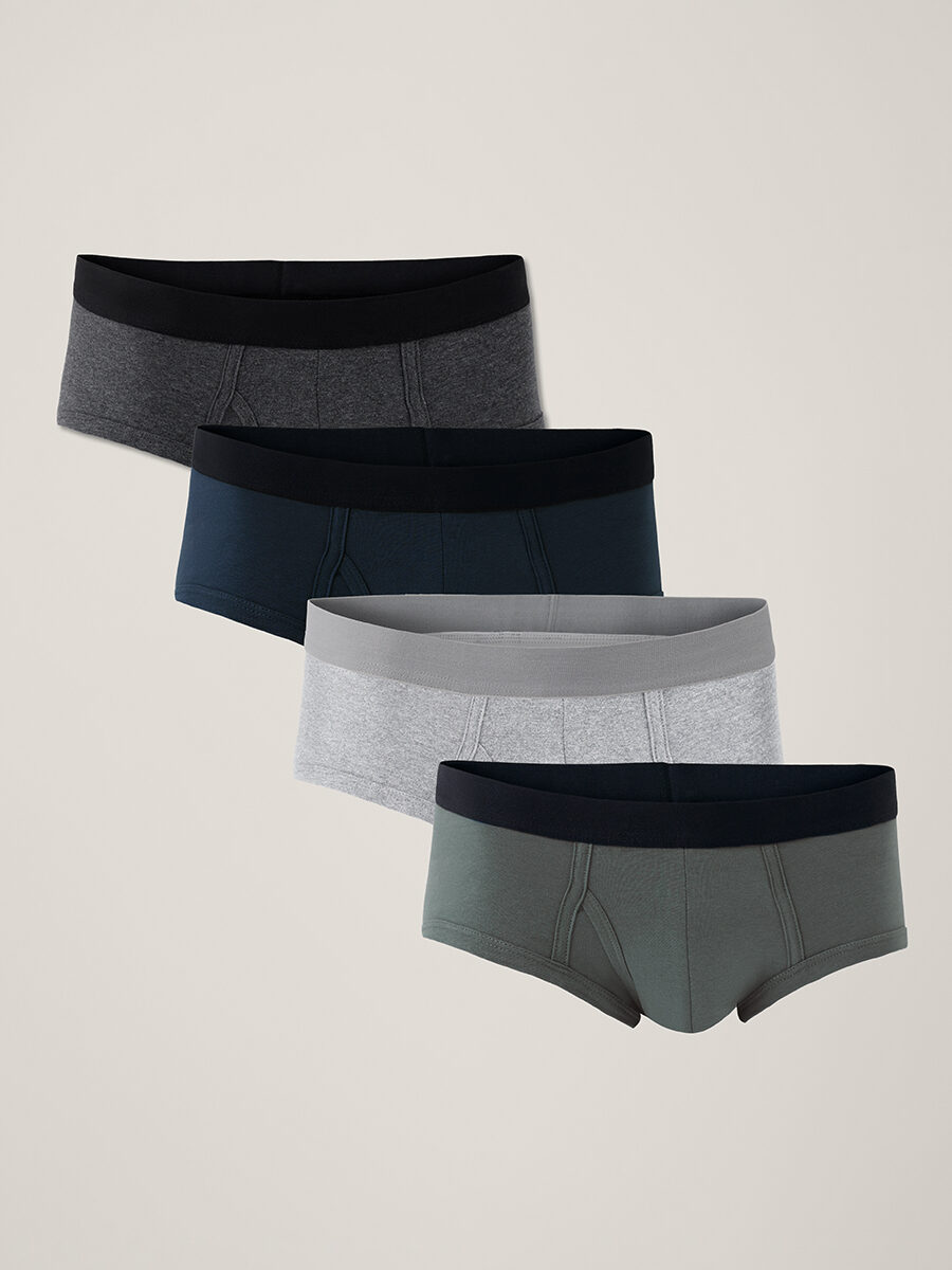 Four pairs of men's boxer briefs in charcoal, navy, light gray, and olive colors, each with a black waistband, are arranged in a staggered row on a plain background.