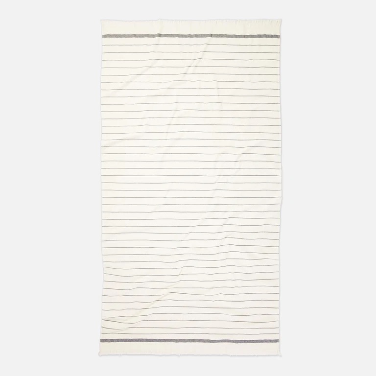 A cream-colored rectangular blanket with thin horizontal black stripes and thicker black borders on the top and bottom edges.