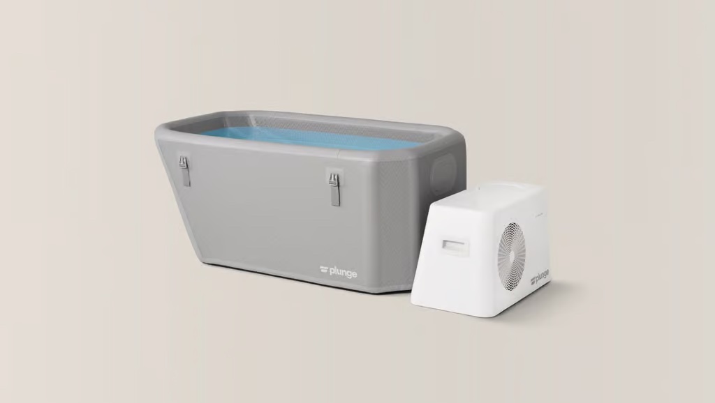 A rectangular gray cold plunge tub filled with water sits next to a white cooling unit on a neutral background.