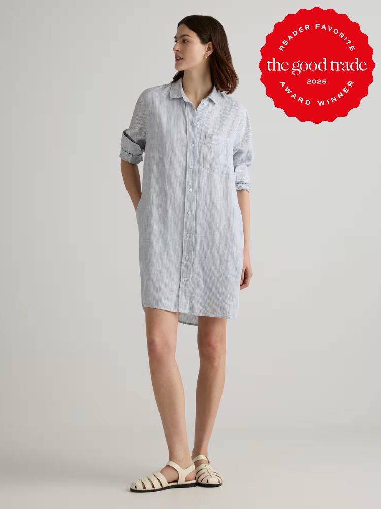 Woman wearing a light blue, long-sleeve button-down shirtdress and sandals, standing against a plain background. "The Good Trade 2025 Reader Favorite Award Winner" badge is displayed.