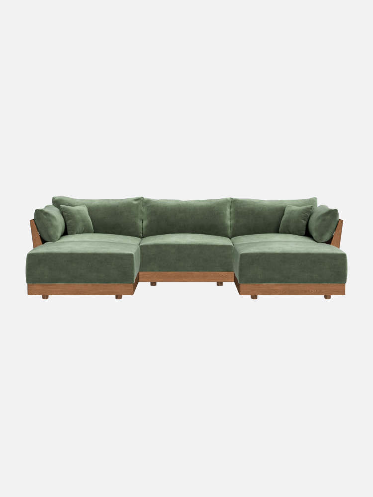 A green L-shaped sectional sofa with wooden base, featuring plush cushions and matching throw pillows, shown against a white background.