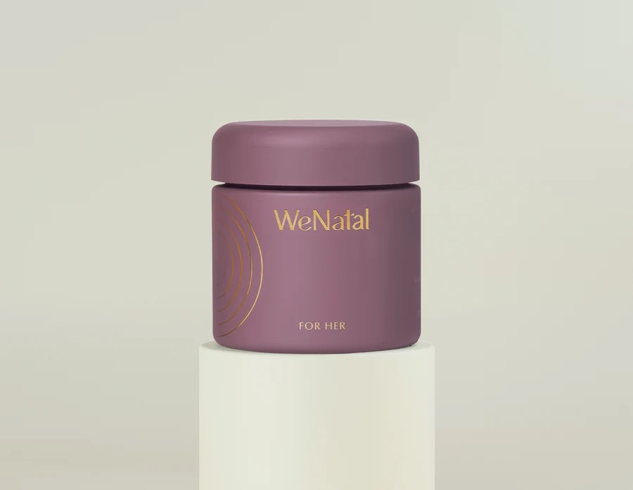A purple jar labeled "WeNatal For Her" with gold lettering sits on a white cylindrical pedestal against a neutral background.