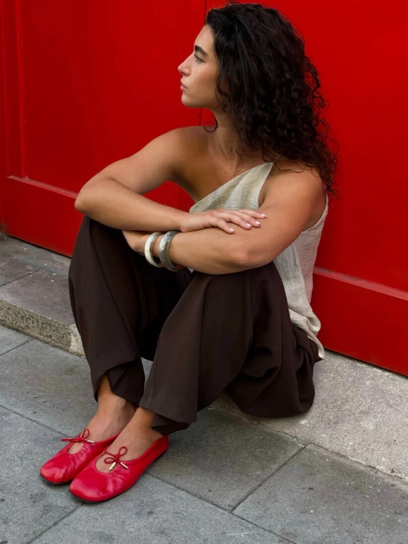 A woman sitting on the ground, effortlessly embodying french girl fashion with her chic and understated style.