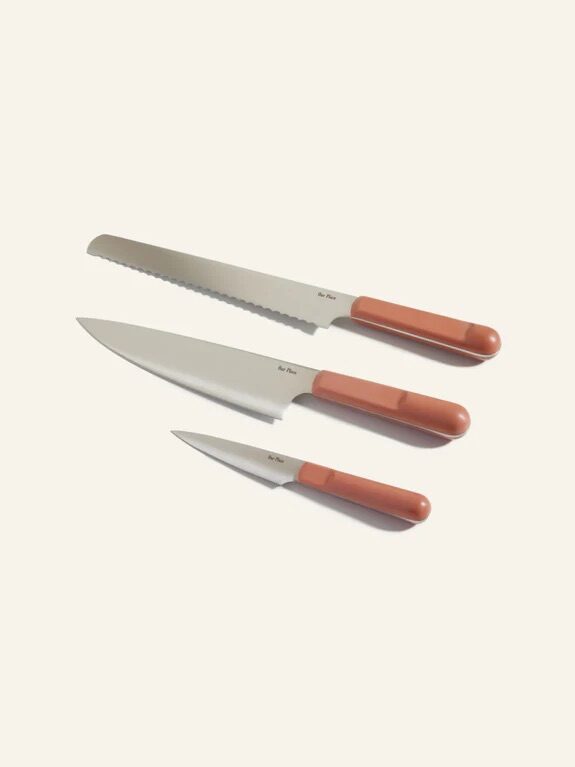 Three kitchen knives with silver blades and brown handles are arranged in a row on a light background.