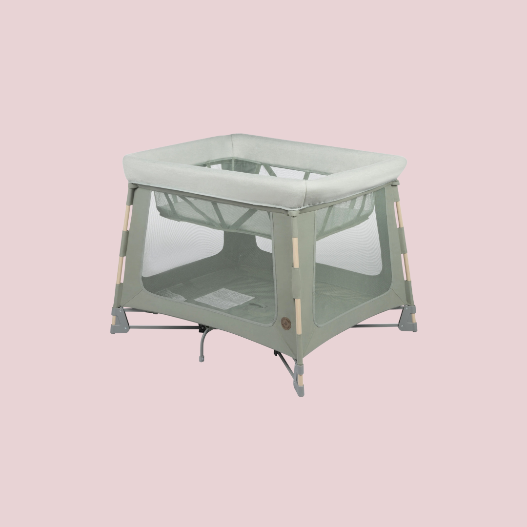 A light gray portable baby playpen with mesh sides and a solid base is shown against a plain pink background.