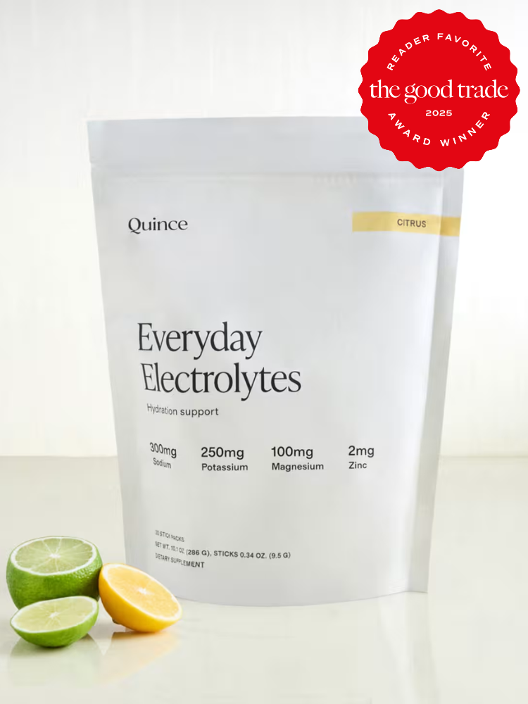 A white pouch labeled "Everyday Electrolytes" by Quince stands behind sliced lime and lemon wedges. A red "The Good Trade Award Winner 2025" badge is in the top right corner.