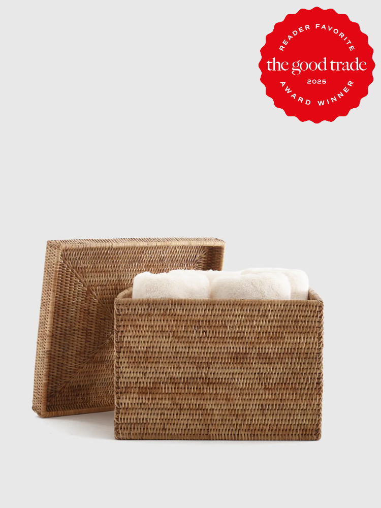 Two woven rectangular storage baskets, one with the lid off, containing white towels. A red "Reader Favorite The Good Trade 2025 Award Winner" badge is in the top right corner.