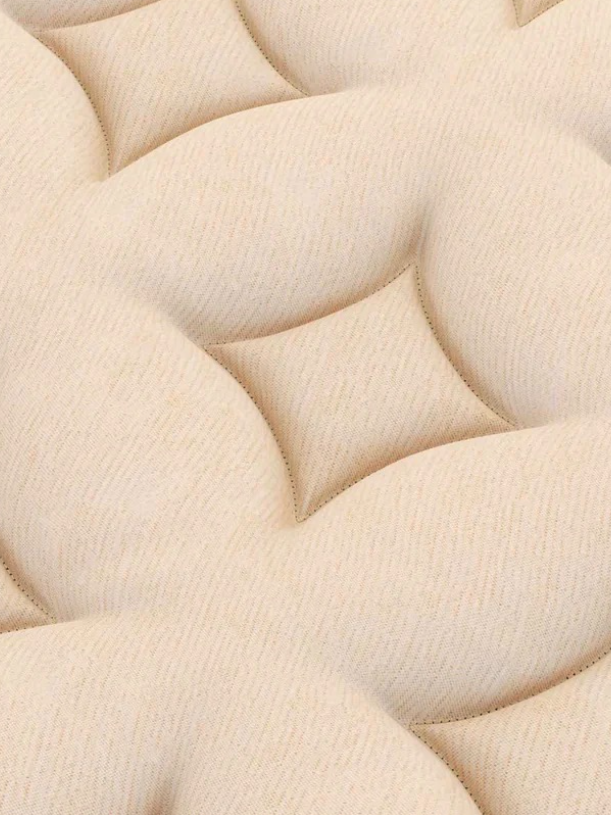 Close-up view of a beige, quilted mattress surface with raised, tufted sections creating a soft, padded texture.