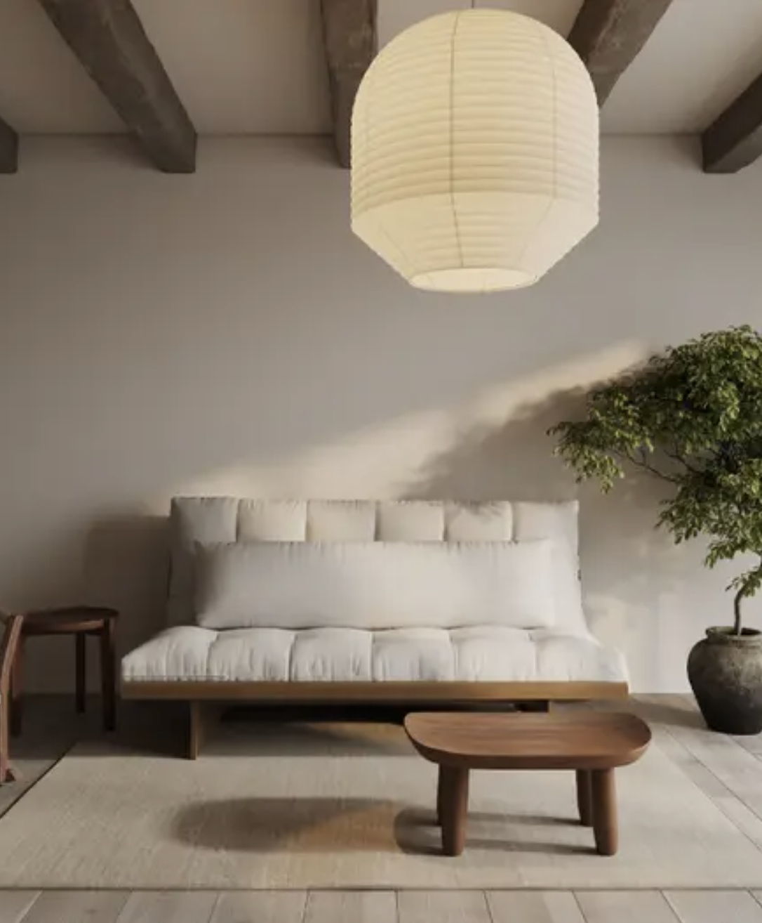 A minimalist living room with a white cushioned sofa, a wooden coffee table, a paper lantern ceiling light, a potted plant, and exposed wooden ceiling beams.