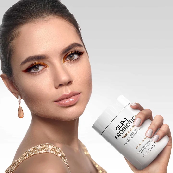 A woman with styled hair and makeup holds a container labeled "GLP-1 Probiotic Trim & Glow" by Codeage against a plain light background.