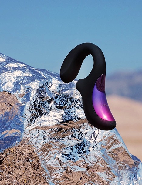 A black and purple curved electronic device rests on crumpled reflective foil outdoors with a blurred desert landscape in the background.