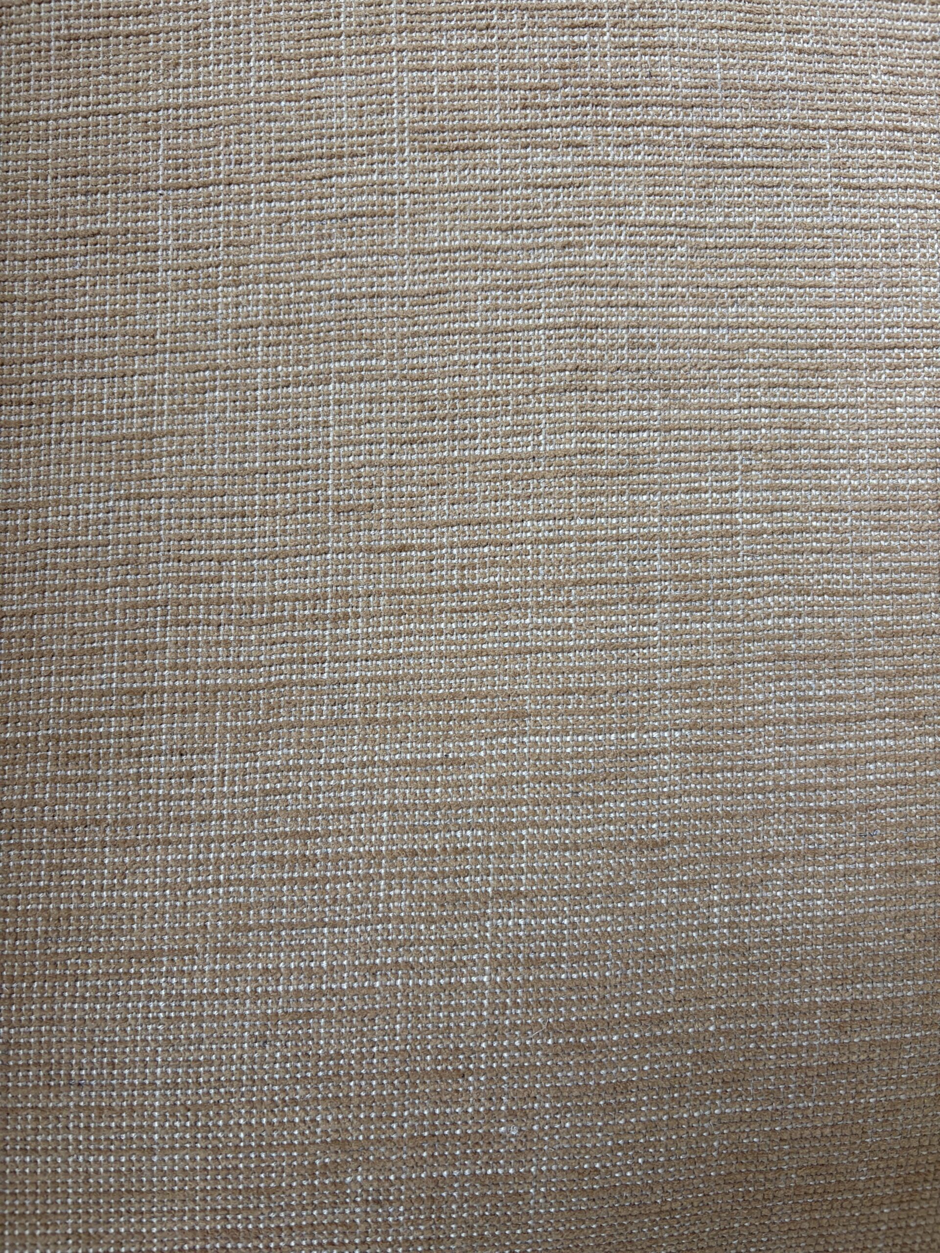 Close-up of a textured beige fabric with a visible woven pattern.
