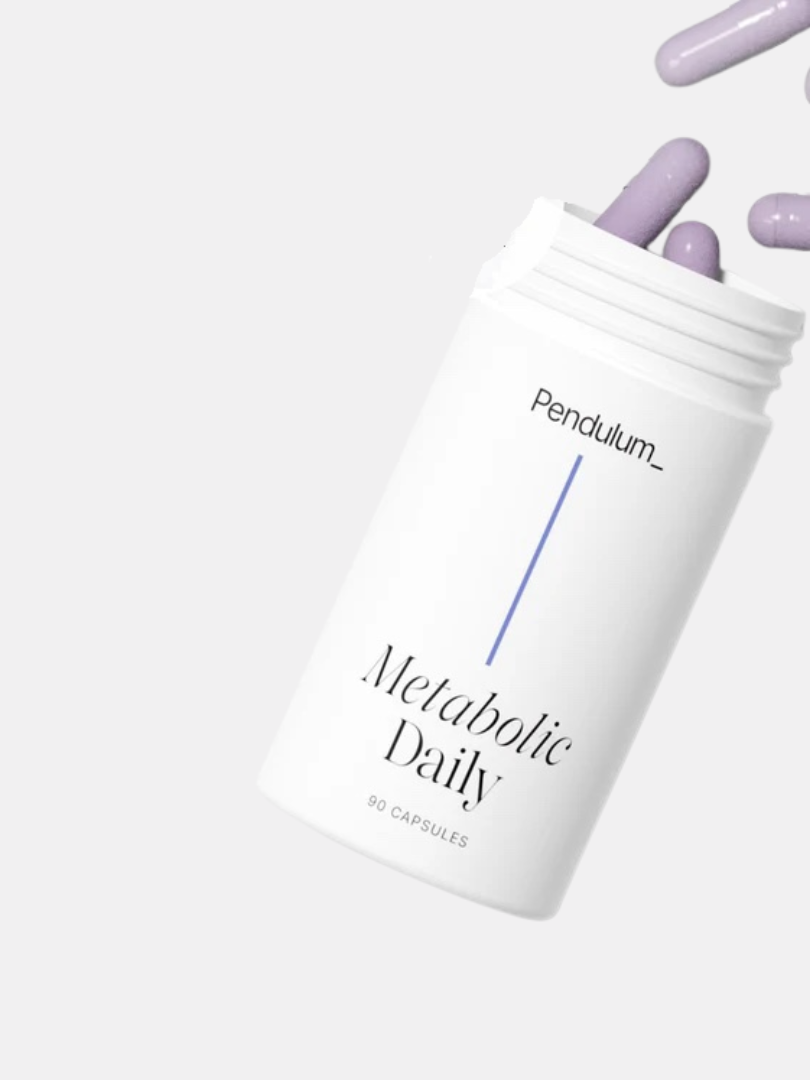 A white bottle labeled "Pendulum Metabolic Daily" lies on its side with purple capsules spilling out.