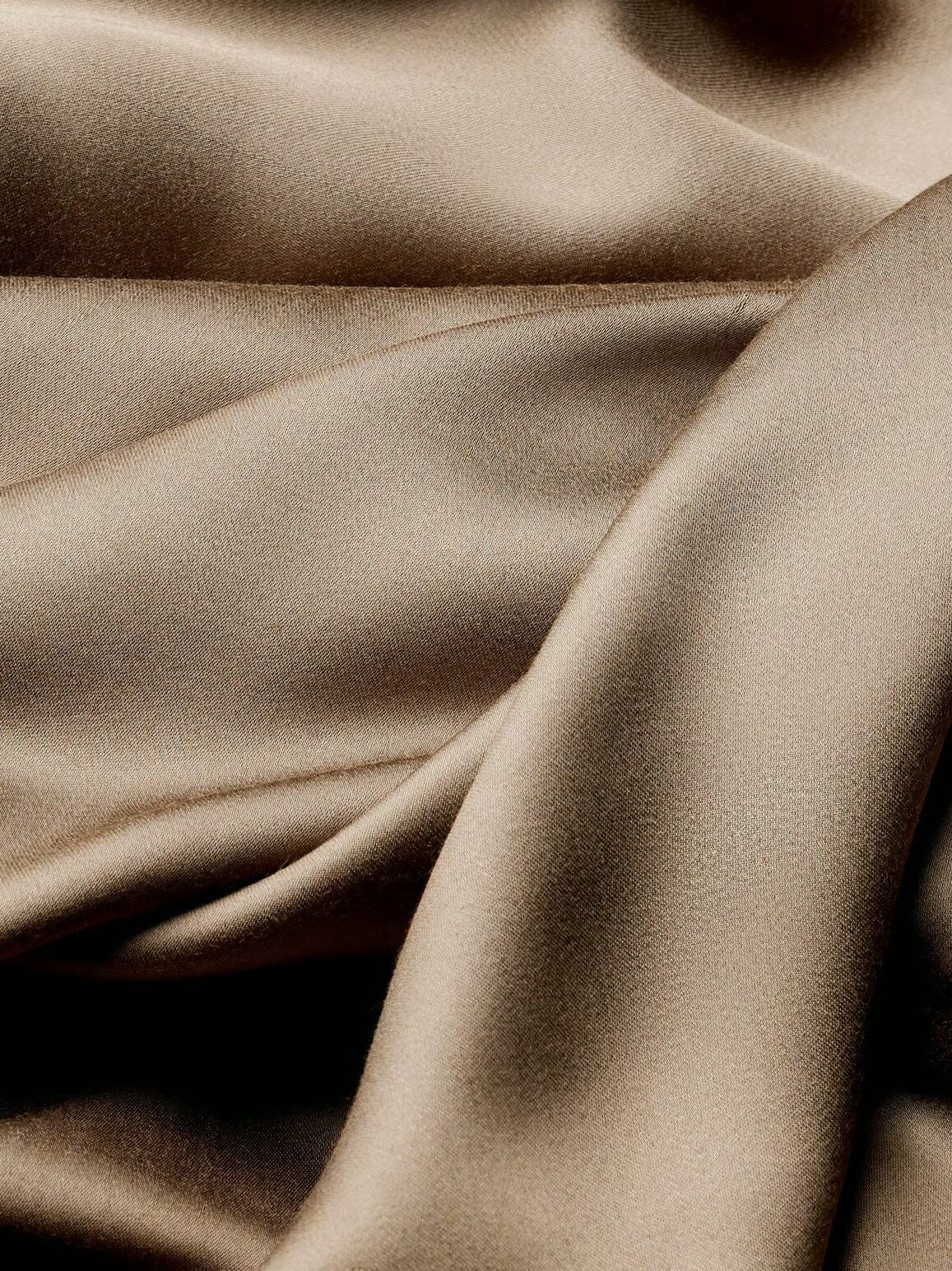 Close-up of smooth, light brown satin fabric with gentle folds and a soft, shiny texture.