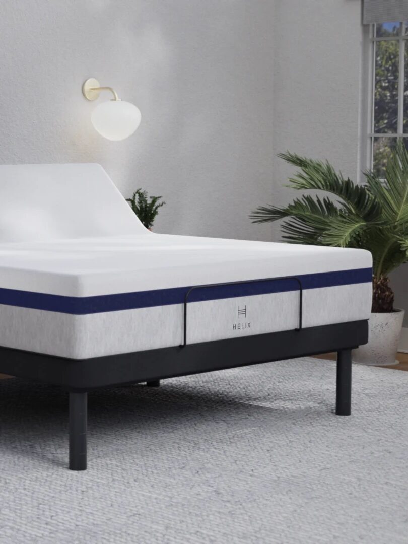 Adjustable bed in a modern bedroom, mattress elevated at the head, with a "Reduce Snoring" label in the top left corner.