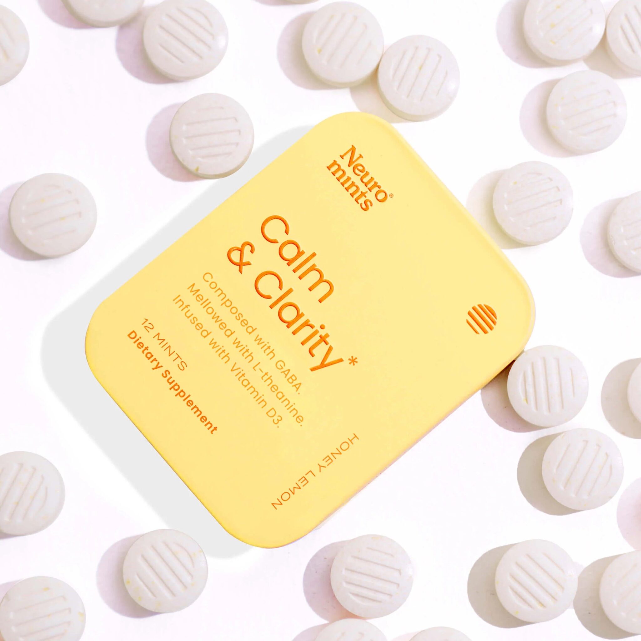 A yellow tin labeled "Neuro mints Calm & Clarity" surrounded by white round tablets on a white background.