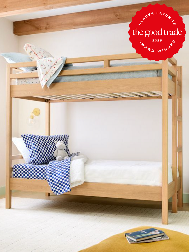 A wooden bunk bed with blue and white bedding in a bright room; a red "Reader Favorite - The Good Trade Award Winner 2025" badge is displayed in the top right corner.