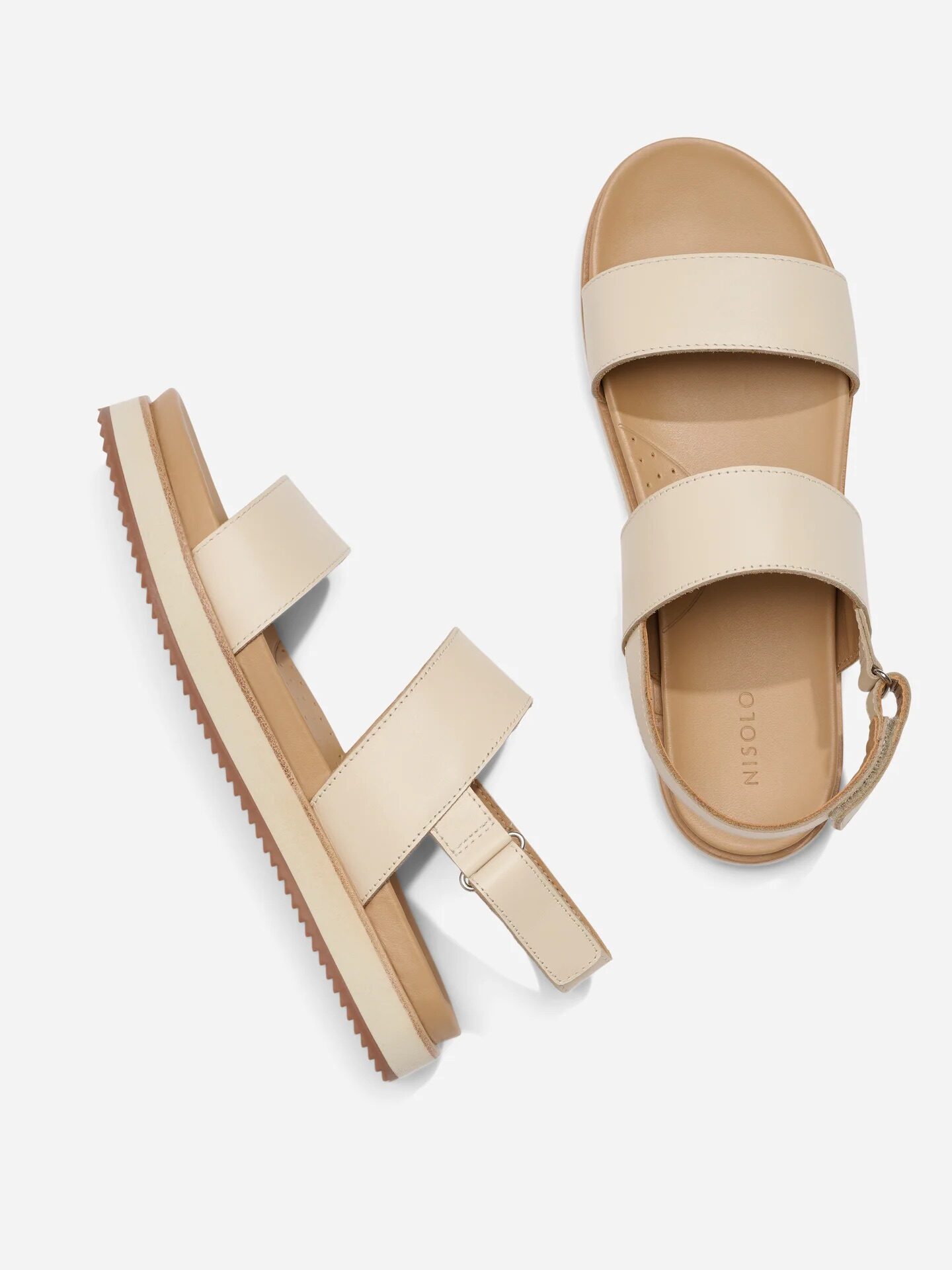 A pair of beige, open-toe sandals with two wide straps and ankle buckle, displayed on a white background.