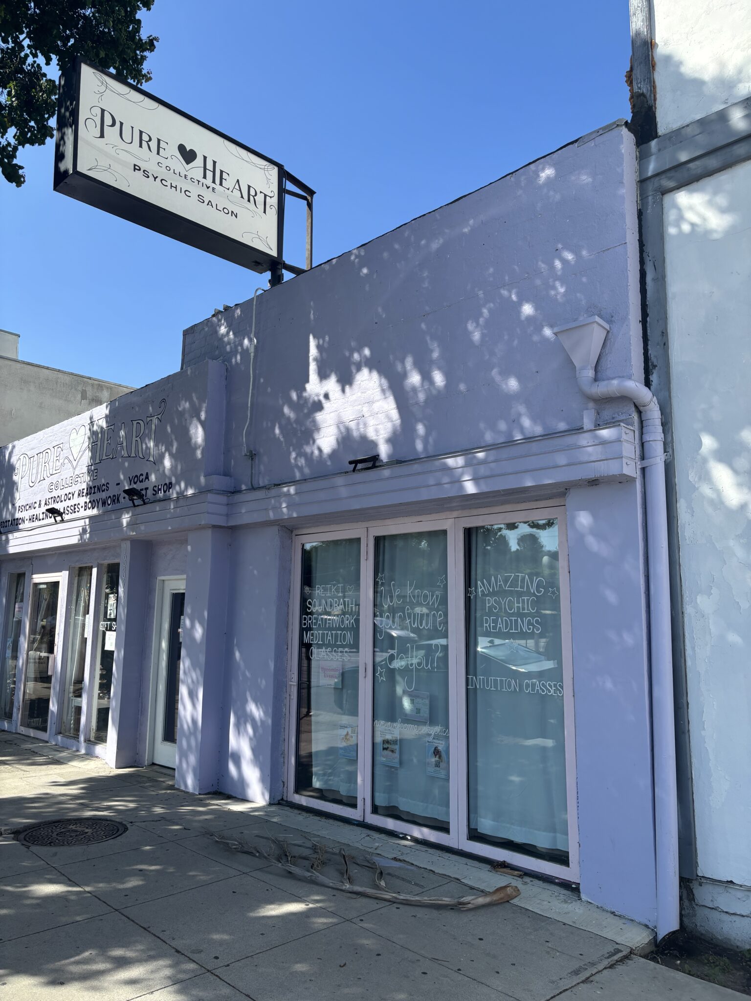 A light purple building with a sign reading "Pure Heart Psychic Salon" and window displays advertising psychic readings and spiritual services.