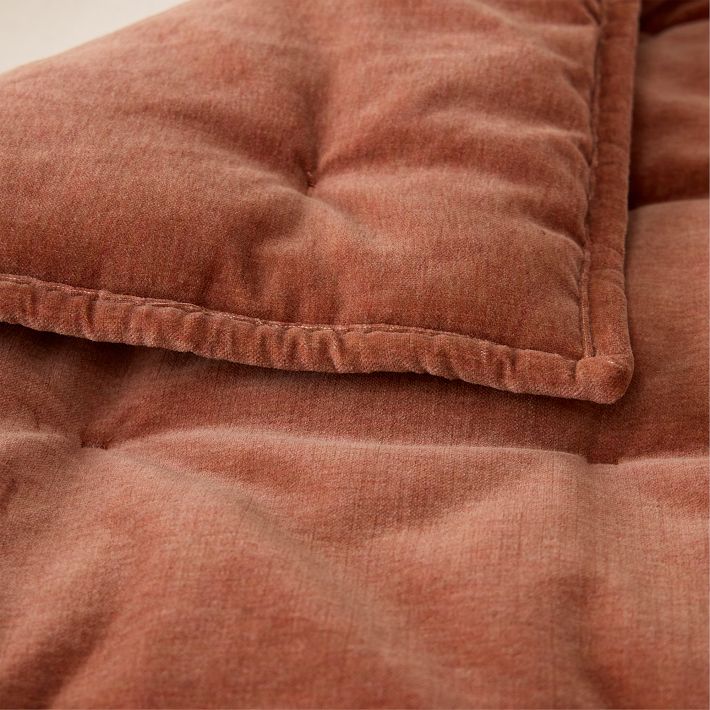 Close-up of a brown, quilted fabric blanket with visible stitching and soft texture.