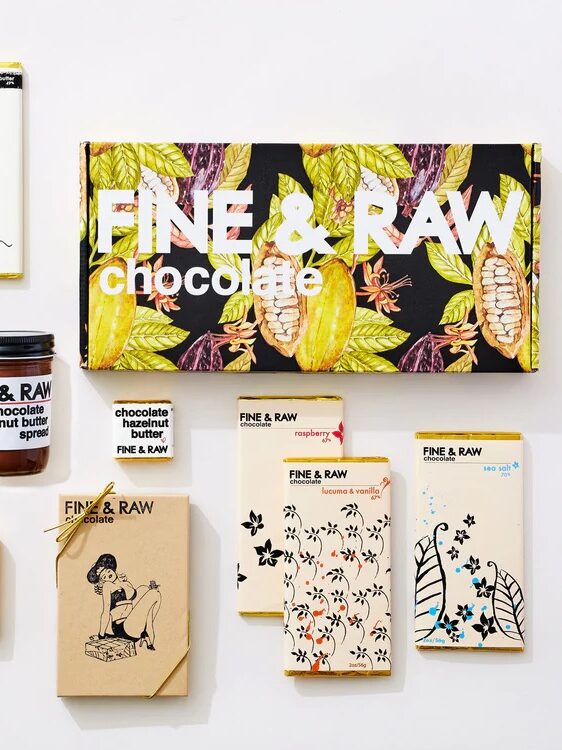 Assorted FINE & RAW chocolate bars and a jar of chocolate hazelnut butter spread arranged on a white surface.