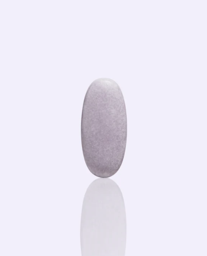 A single, oval-shaped, light purple tablet standing upright against a plain light background with a faint reflection below it.
