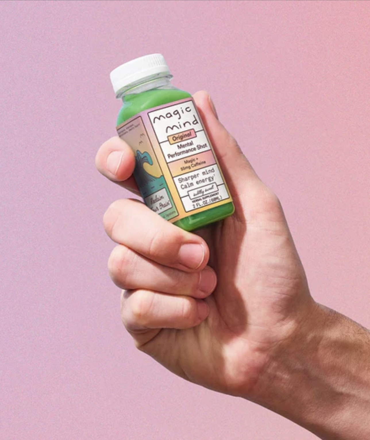 A hand holds a small bottle labeled "Magic Mind Original Matcha Performance Shot" against a pink gradient background.