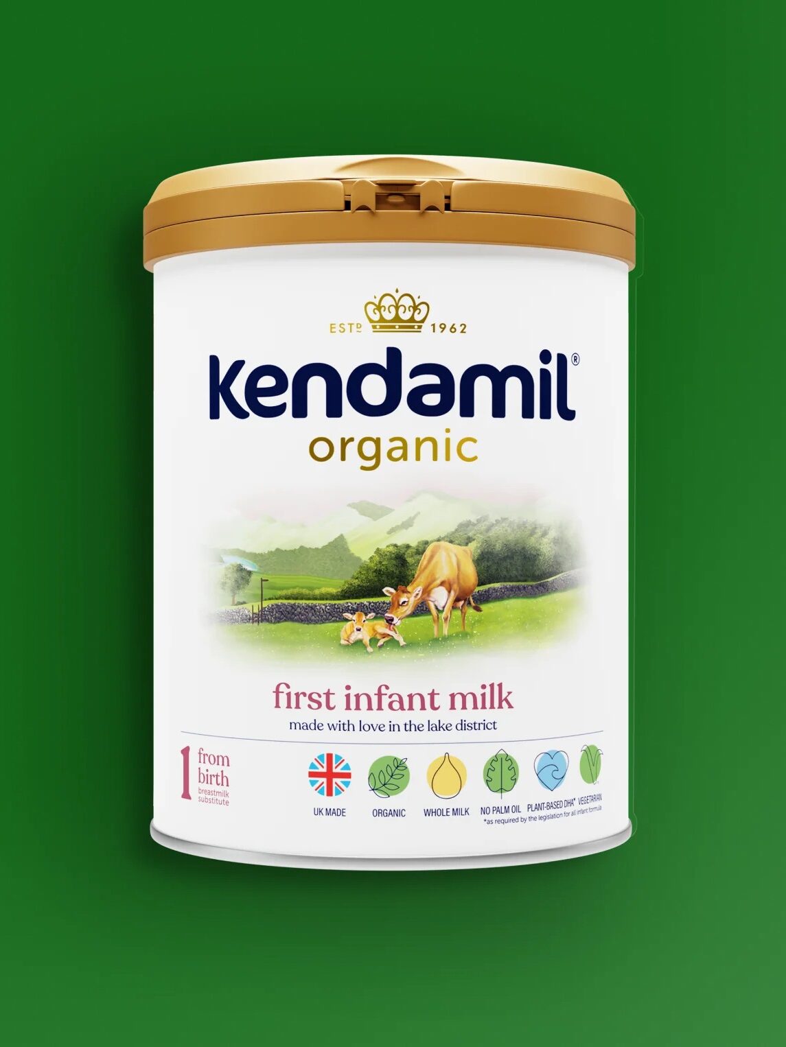 A can of Kendamil Organic First Infant Milk with a gold lid, showing a pasture scene with cows, on a green background.