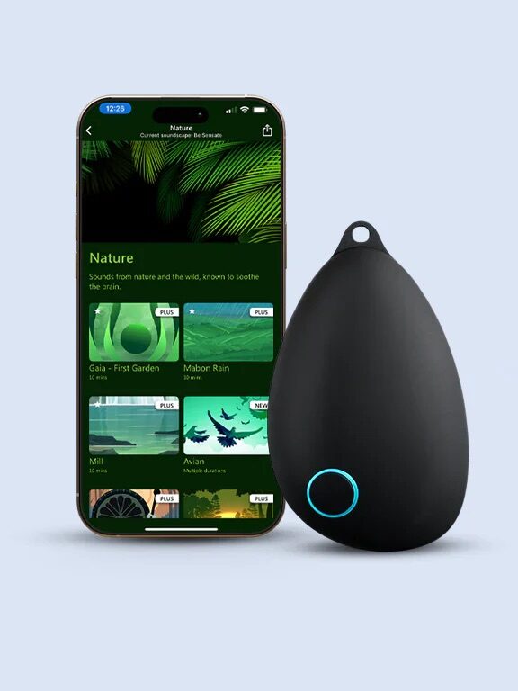 A smartphone displaying a nature sounds app stands next to a black, teardrop-shaped electronic device with a blue-lit circular button.