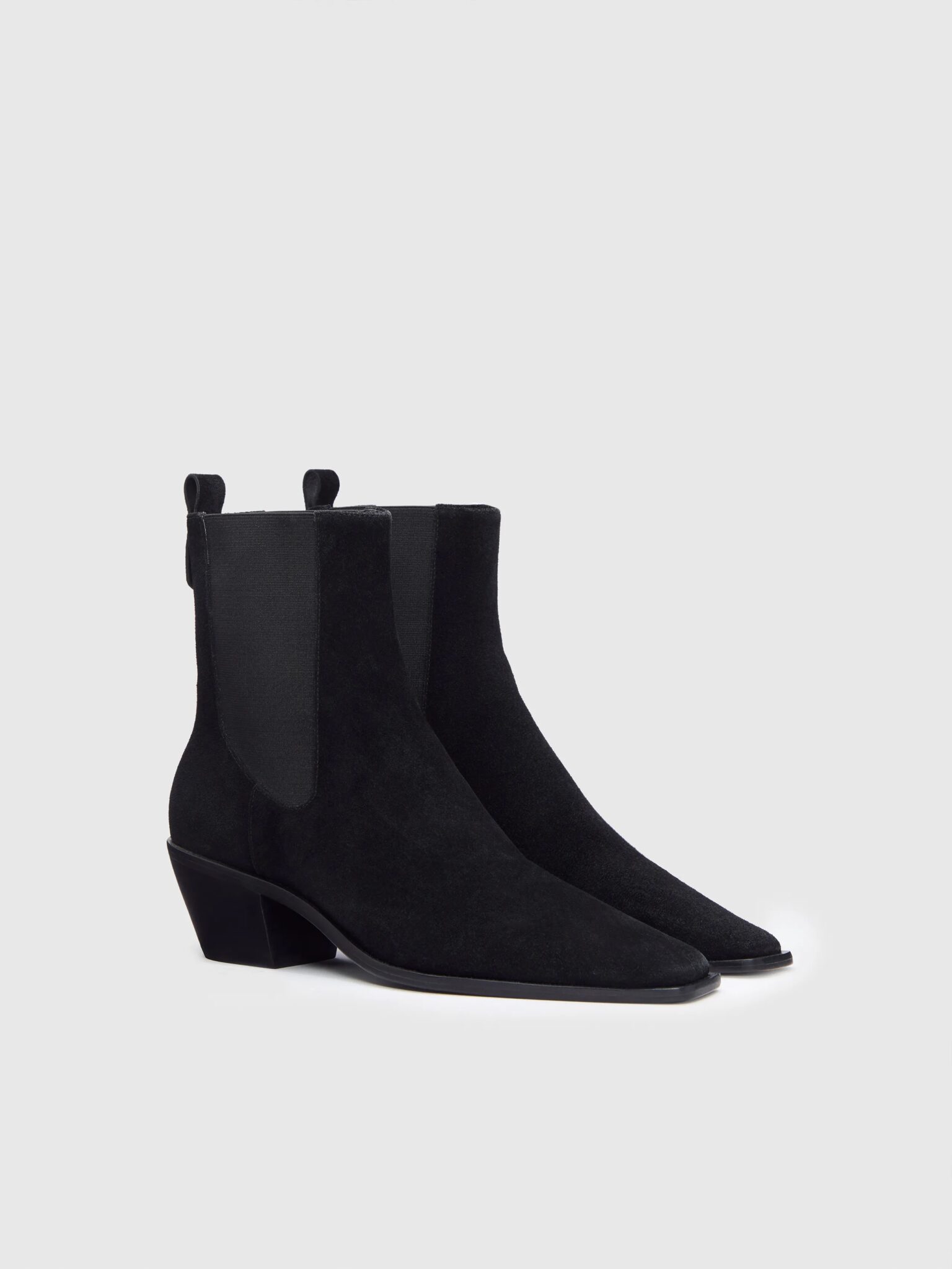 A pair of black suede ankle boots with pointed toes, elastic side panels, pull tabs, and low block heels on a plain light background.