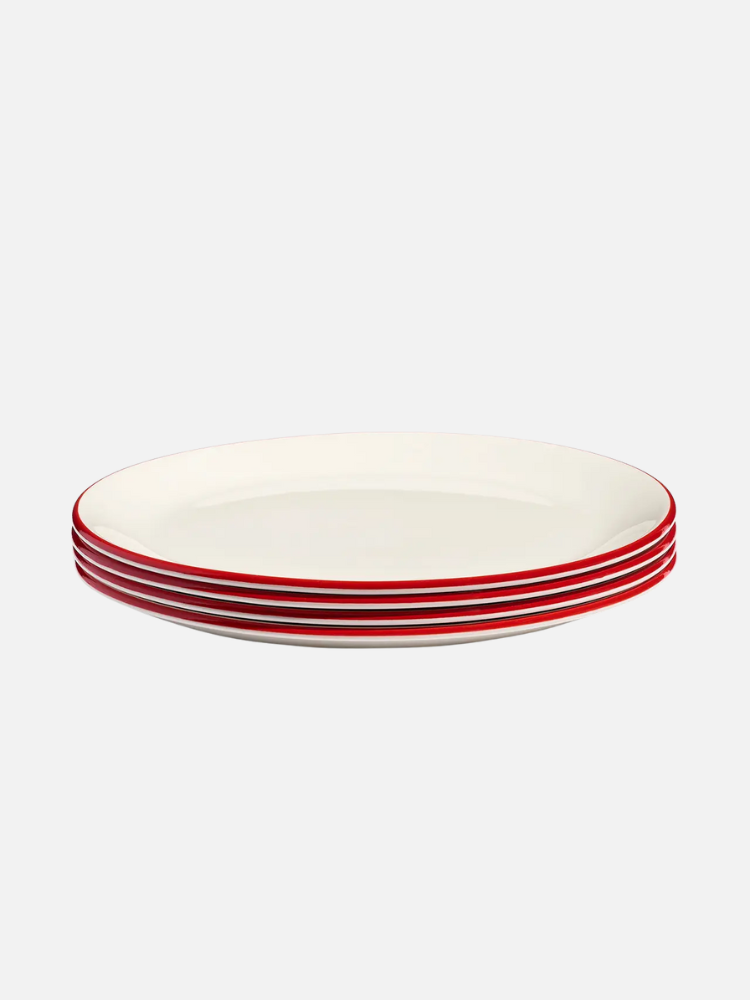 Four stacked white dinner plates with red rims, viewed from the side against a plain light background.