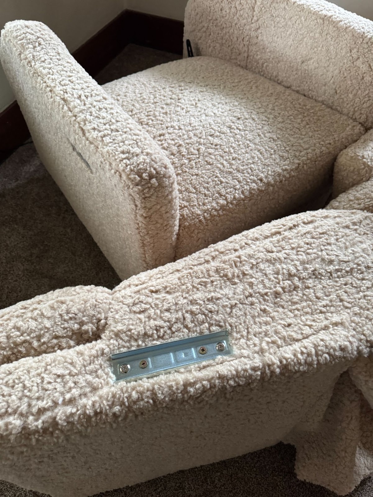 Two pieces of a beige, textured sectional sofa are separated, showing the metal connector bracket on one section.