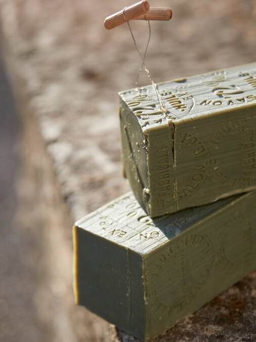 Two green rectangular blocks of military-style plastic explosive sit on a stone surface, with a pull detonator inserted into one block.