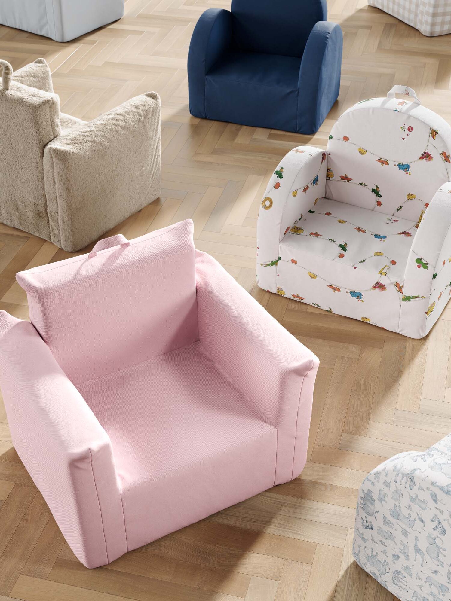 Several small, upholstered children's armchairs in different colors and patterns are arranged on a light wood floor.