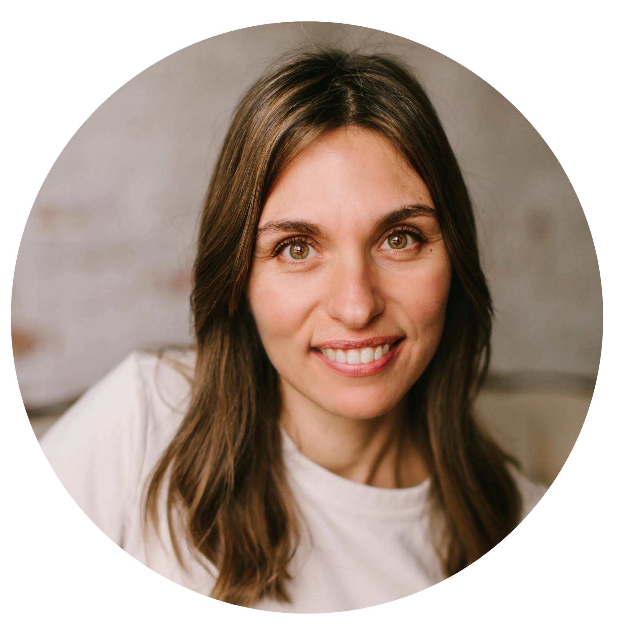 A woman with long brown hair and a white shirt smiles at the camera against a neutral background.