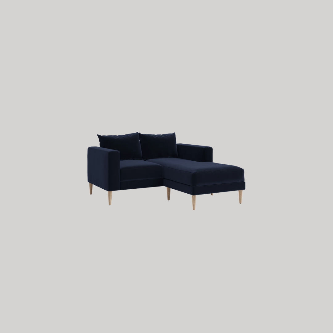 Dark blue sectional sofa with wooden legs and two matching cushions, set against a plain light gray background.