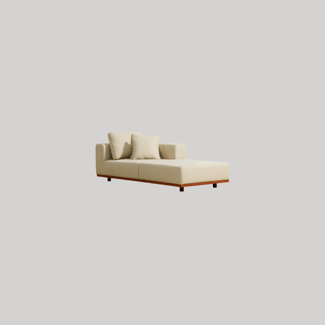 A beige chaise lounge with two matching throw pillows, set against a plain light gray background.