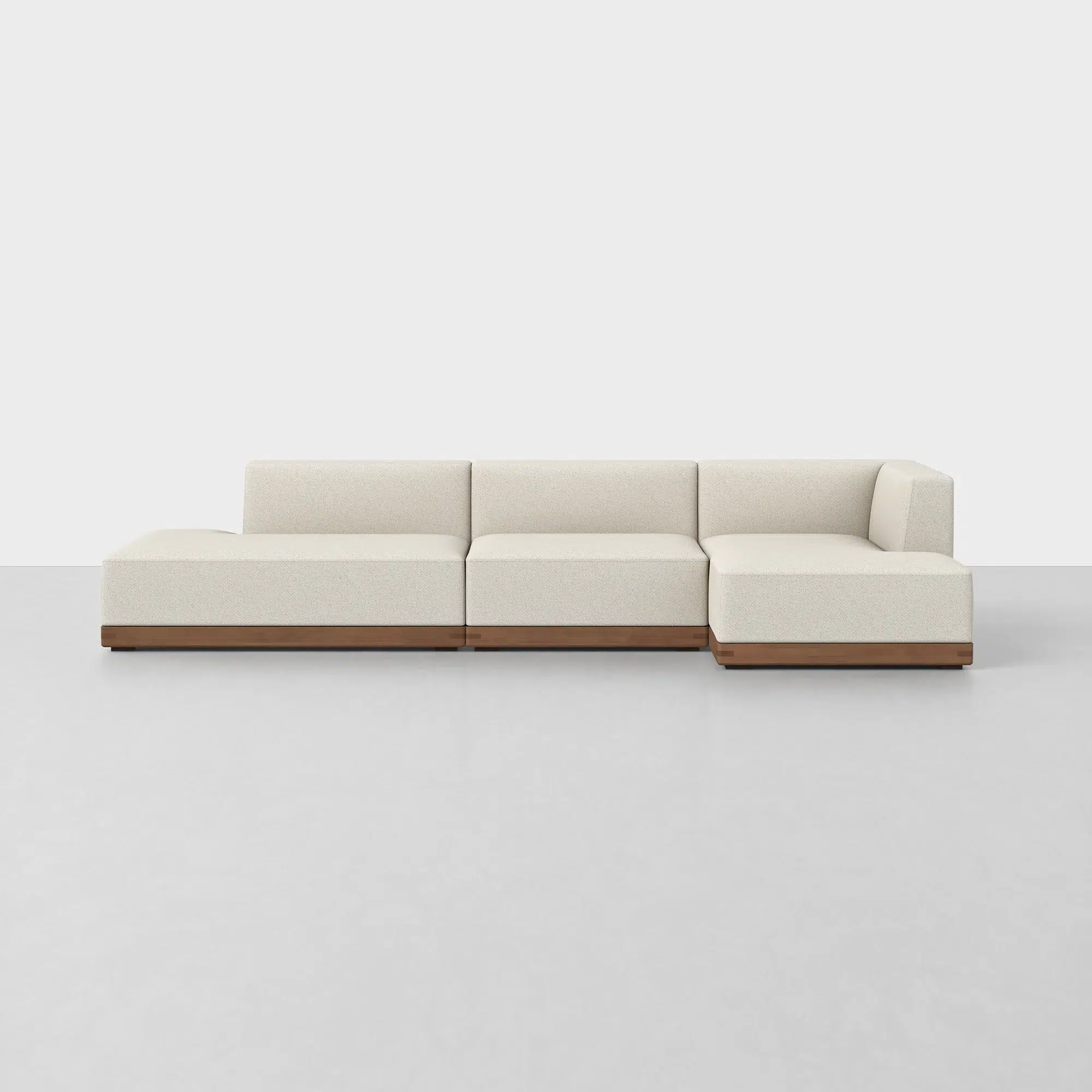 A modern, modular cream-colored sectional sofa with a wooden base, set against a plain white background.